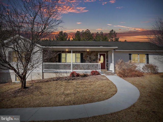 ranch-style home with a yard, stone siding, and a porch