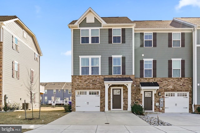 townhome / multi-family property featuring driveway, stone siding, and an attached garage