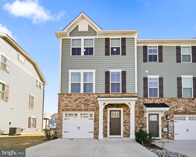 view of property featuring cooling unit, stone siding, driveway, and an attached garage