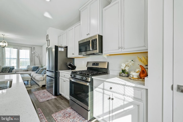 kitchen with dark wood-style flooring, a notable chandelier, appliances with stainless steel finishes, open floor plan, and white cabinetry