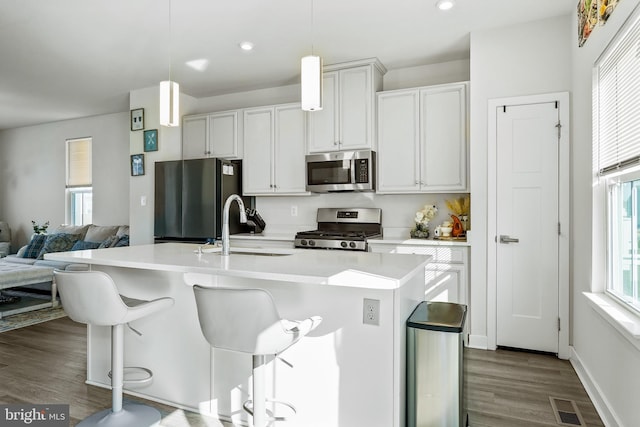 kitchen featuring stainless steel appliances, a sink, visible vents, light countertops, and dark wood-style floors