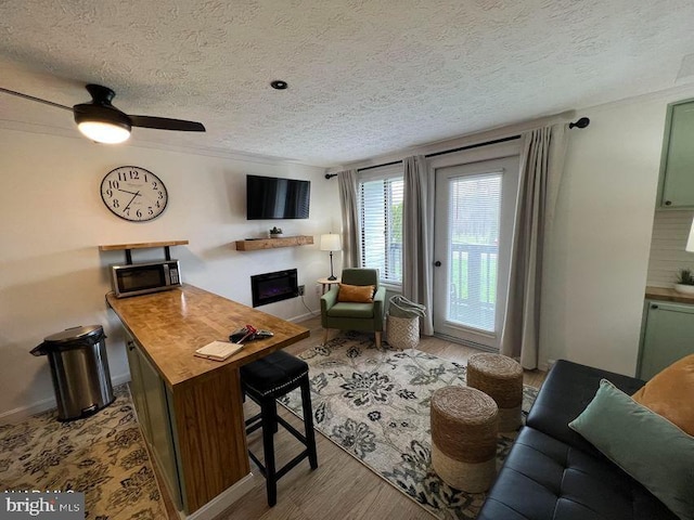 living room with a fireplace, a textured ceiling, baseboards, and wood finished floors