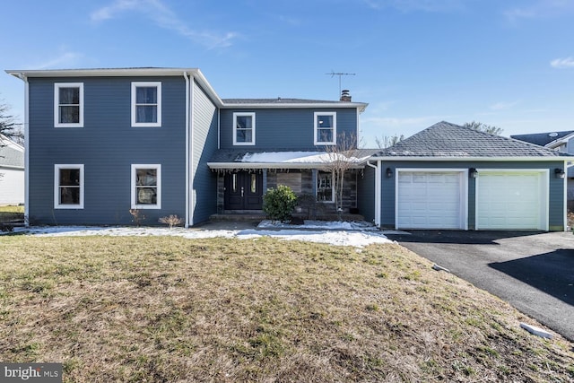 traditional-style home featuring driveway, a front lawn, a chimney, and an attached garage