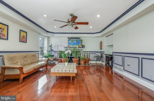 sitting room with a wainscoted wall, ornamental molding, a decorative wall, and wood finished floors