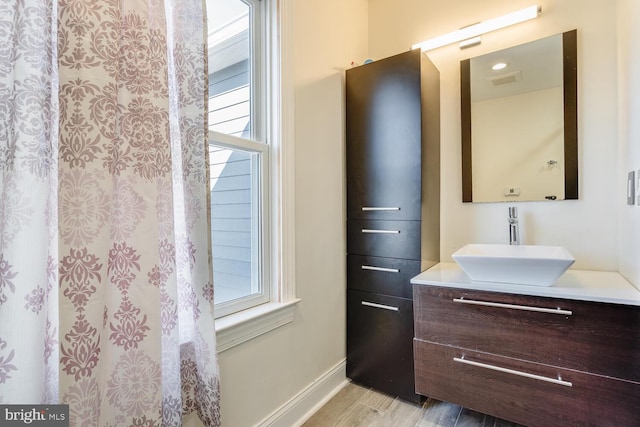 bathroom featuring plenty of natural light, vanity, baseboards, and wood finished floors