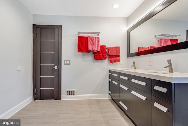 bathroom featuring double vanity, baseboards, visible vents, and a sink