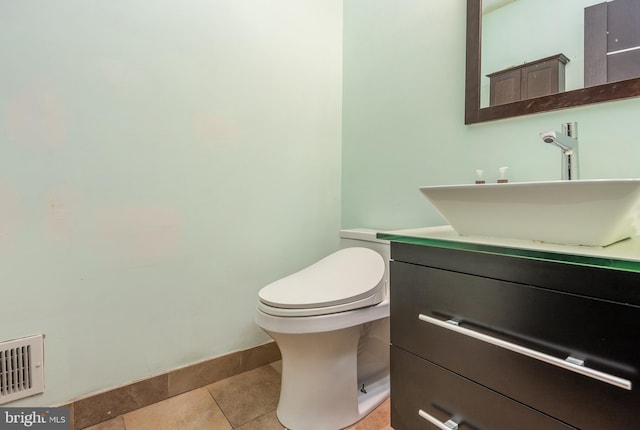 bathroom with visible vents, toilet, vanity, tile patterned flooring, and baseboards