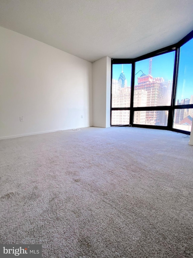 spare room featuring a view of city, floor to ceiling windows, carpet flooring, and a textured ceiling