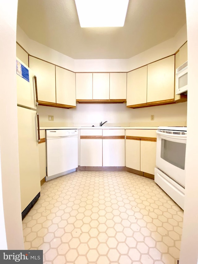 kitchen with light countertops, white appliances, light floors, and a sink