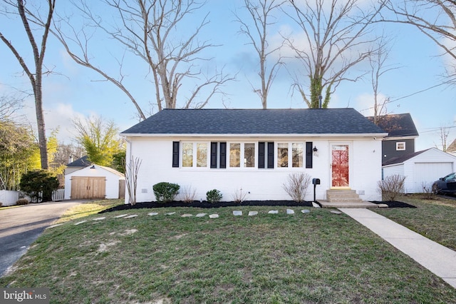 view of front of house with a detached garage, a front lawn, an outbuilding, and brick siding