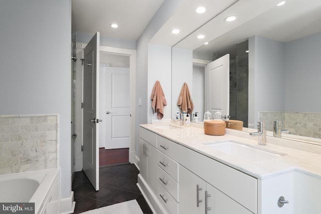 full bathroom with double vanity, a garden tub, tile patterned flooring, and a sink