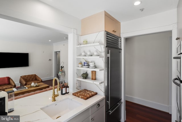 kitchen with dark wood-style floors, open floor plan, built in refrigerator, light stone countertops, and a sink