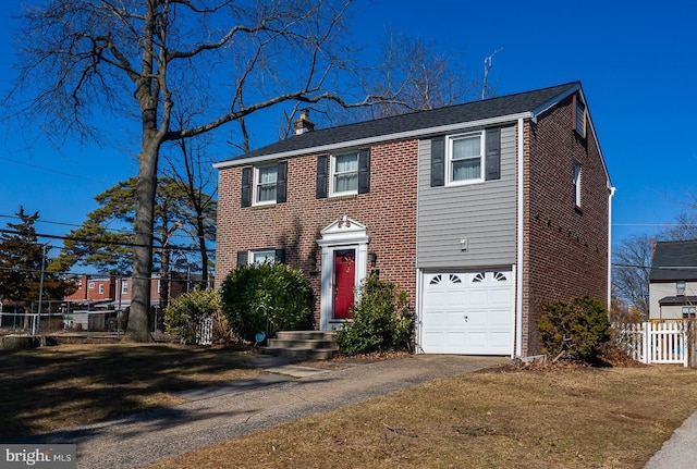 colonial-style house featuring an attached garage, brick siding, fence, a chimney, and a front yard