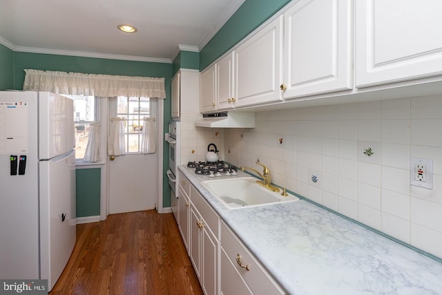 kitchen featuring white appliances, a sink, white cabinets, light countertops, and decorative backsplash