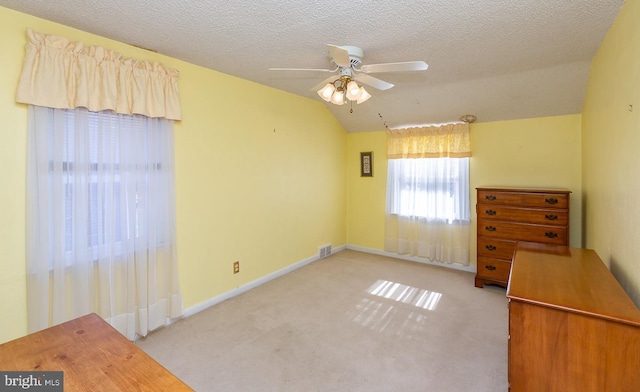 unfurnished room with lofted ceiling, a textured ceiling, visible vents, and carpet flooring