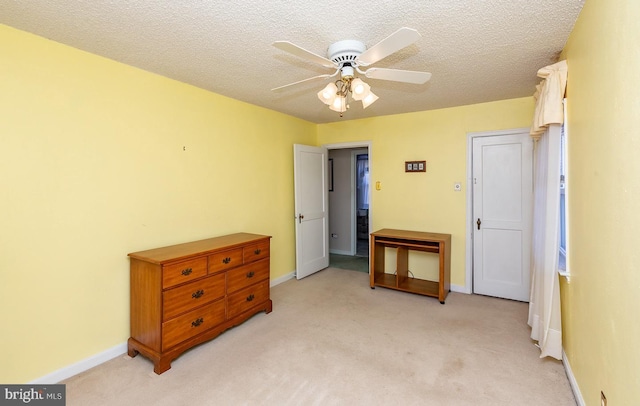 bedroom with light colored carpet, a textured ceiling, and baseboards