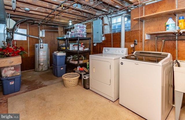 laundry room with laundry area, gas water heater, washing machine and dryer, and electric panel