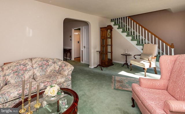 carpeted living room featuring baseboards, stairs, and arched walkways