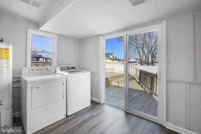 laundry area with washer and clothes dryer, visible vents, water heater, wood finished floors, and laundry area