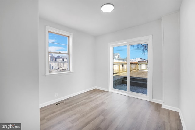 spare room with visible vents, baseboards, and wood finished floors