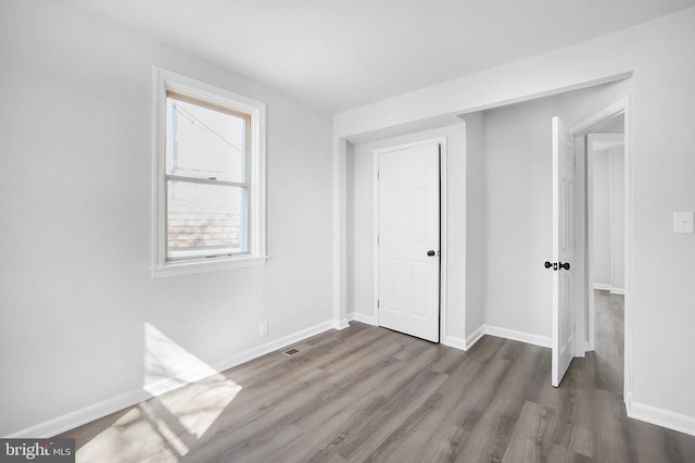 unfurnished bedroom featuring wood finished floors, visible vents, and baseboards