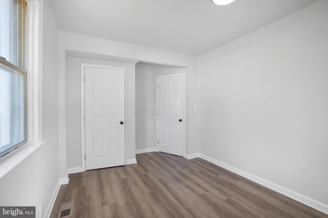 unfurnished bedroom with baseboards, visible vents, and dark wood-style flooring