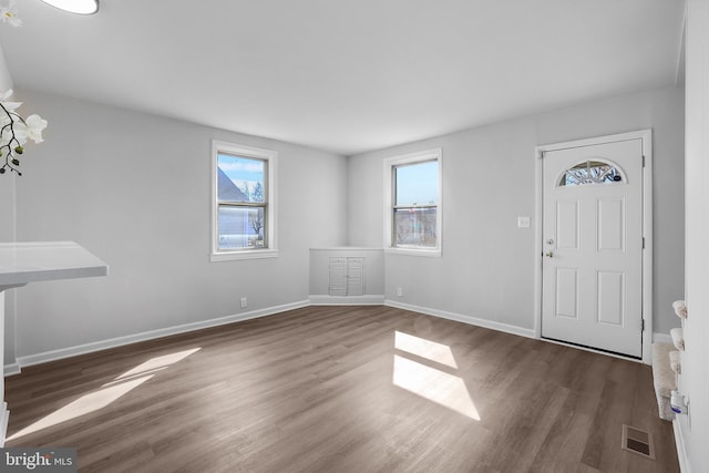 foyer with baseboards, visible vents, and wood finished floors