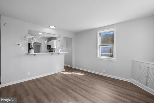 unfurnished living room featuring dark wood finished floors and baseboards