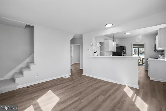 living area with stairway, baseboards, visible vents, and wood finished floors