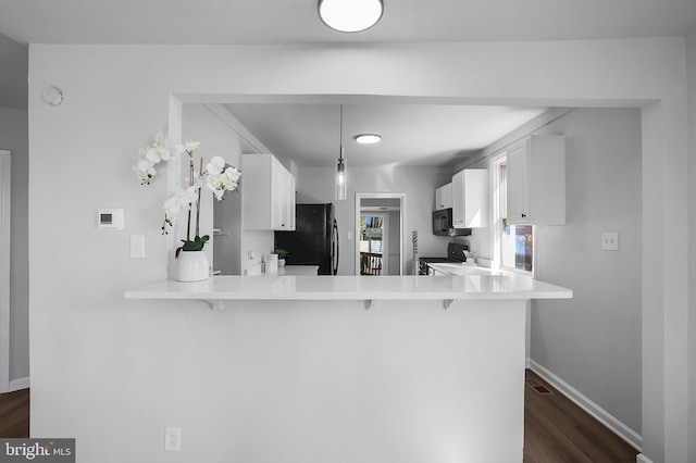 kitchen featuring a breakfast bar area, white cabinets, a peninsula, and black appliances