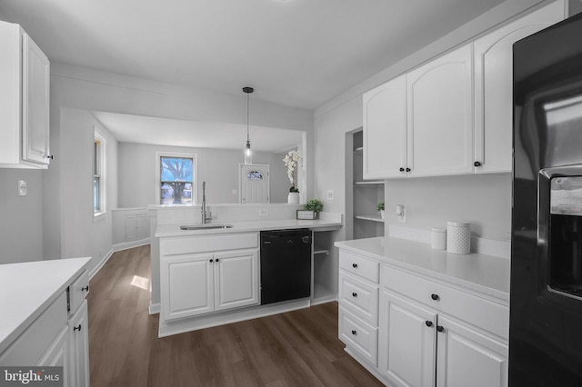 kitchen with black appliances, dark wood finished floors, a sink, and light countertops