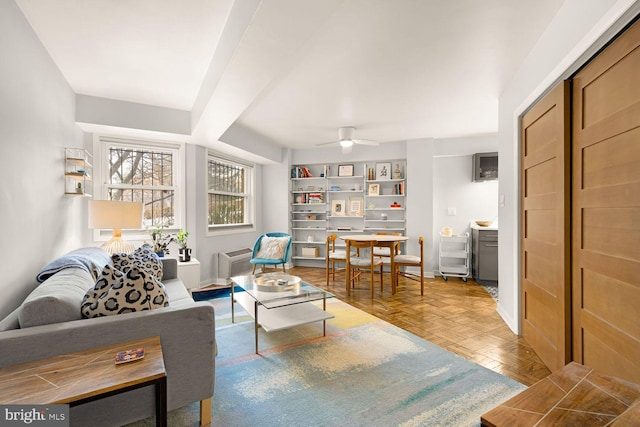 living area with baseboards and a ceiling fan