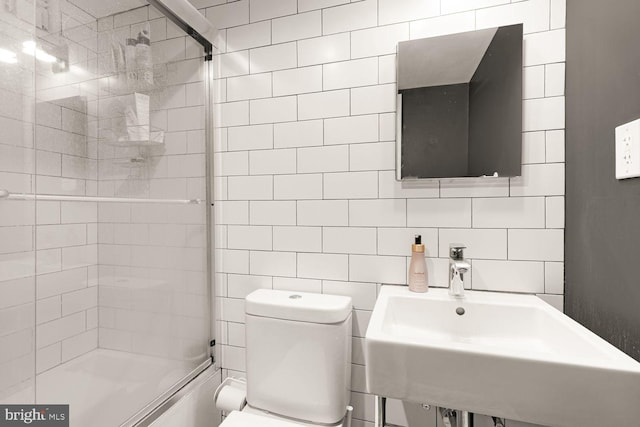 full bathroom featuring tile walls, tasteful backsplash, toilet, an enclosed shower, and a sink