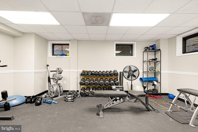 workout area featuring a paneled ceiling and baseboards