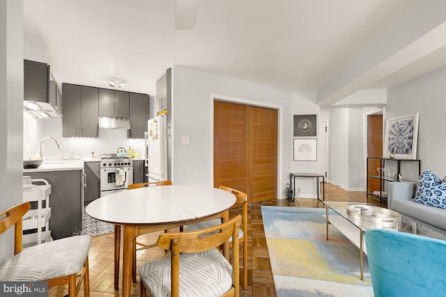 kitchen featuring high end stove, under cabinet range hood, stacked washer and dryer, a sink, and freestanding refrigerator