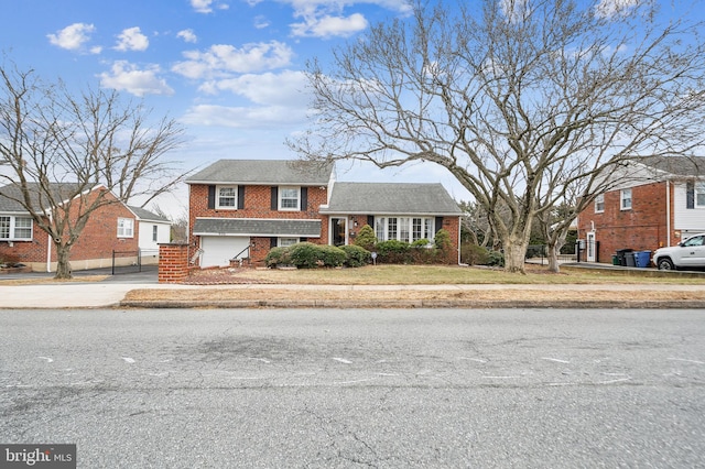 tri-level home with brick siding, driveway, an attached garage, and fence