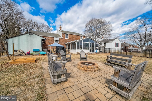 back of house with a patio, a chimney, a sunroom, fence, and a fire pit