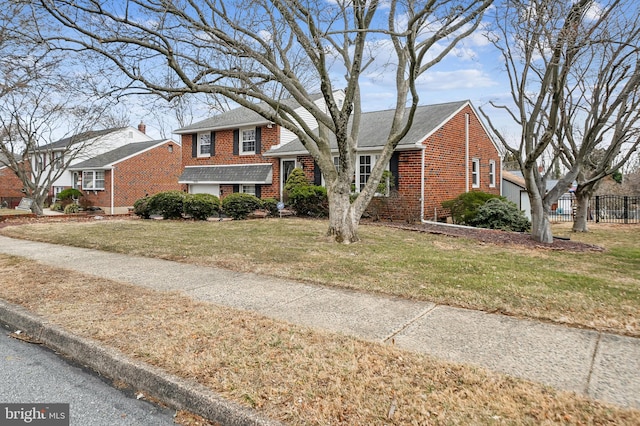 split level home featuring brick siding, a front yard, and fence