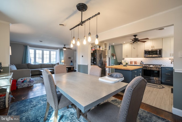 dining room with visible vents, ornamental molding, dark wood finished floors, and a ceiling fan