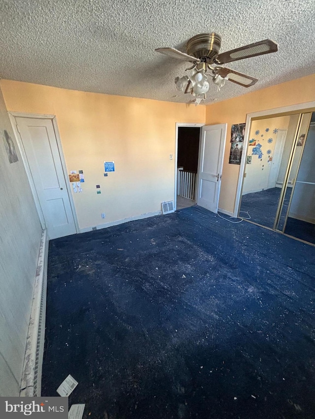 unfurnished room featuring carpet floors, visible vents, ceiling fan, and a textured ceiling