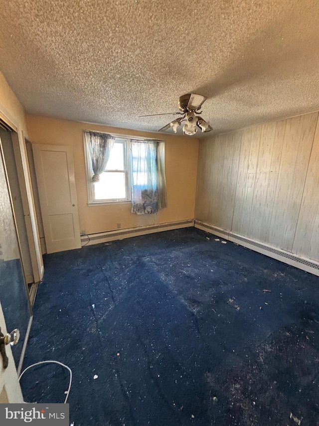 carpeted empty room with a baseboard radiator and a textured ceiling