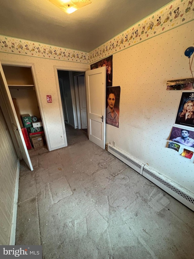 unfurnished bedroom featuring a baseboard heating unit and wallpapered walls