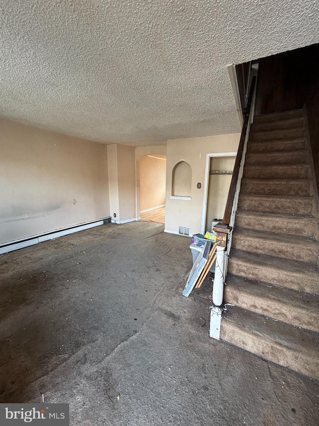 interior space with a textured ceiling, stairway, a baseboard radiator, and visible vents