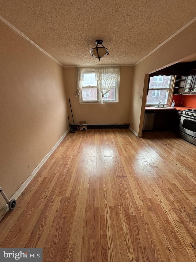 unfurnished living room featuring light wood-style floors, crown molding, a textured ceiling, and baseboards