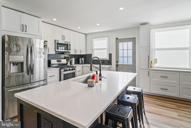 kitchen with tasteful backsplash, light wood-style flooring, a breakfast bar, stainless steel appliances, and a sink