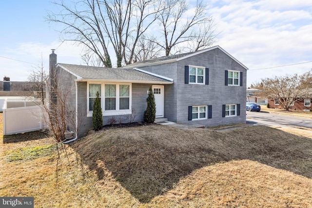 split level home with fence and a chimney