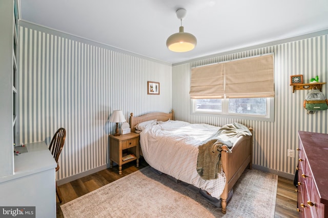 bedroom featuring wood finished floors, baseboards, and wallpapered walls