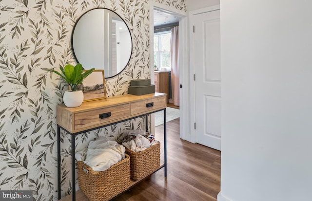 hallway with wood finished floors and wallpapered walls