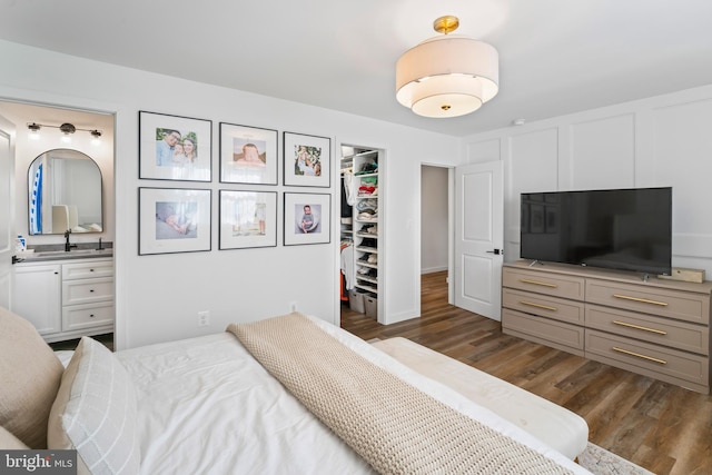 bedroom featuring a spacious closet, a closet, dark wood finished floors, and connected bathroom