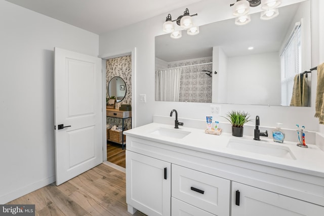 full bath featuring a shower with curtain, double vanity, a sink, and wood finished floors